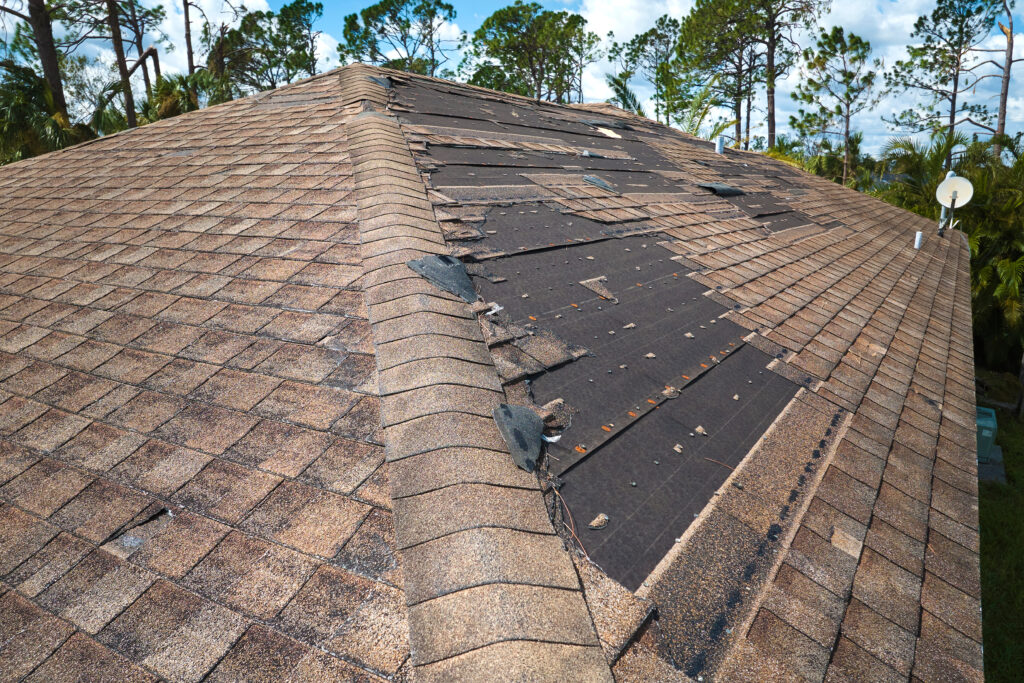roof financing Damaged house roof with missing shingles after hurricane Ian in Florida. Consequences of natural disaster.