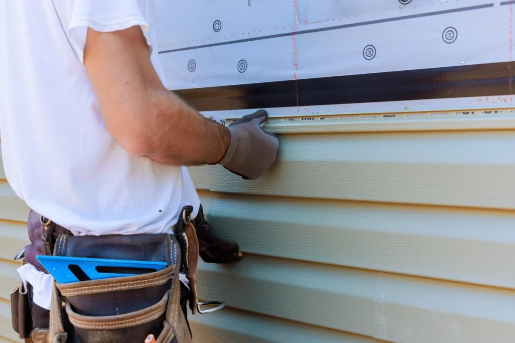 worker hanging vinyl siding panelling on a new siding installation project
