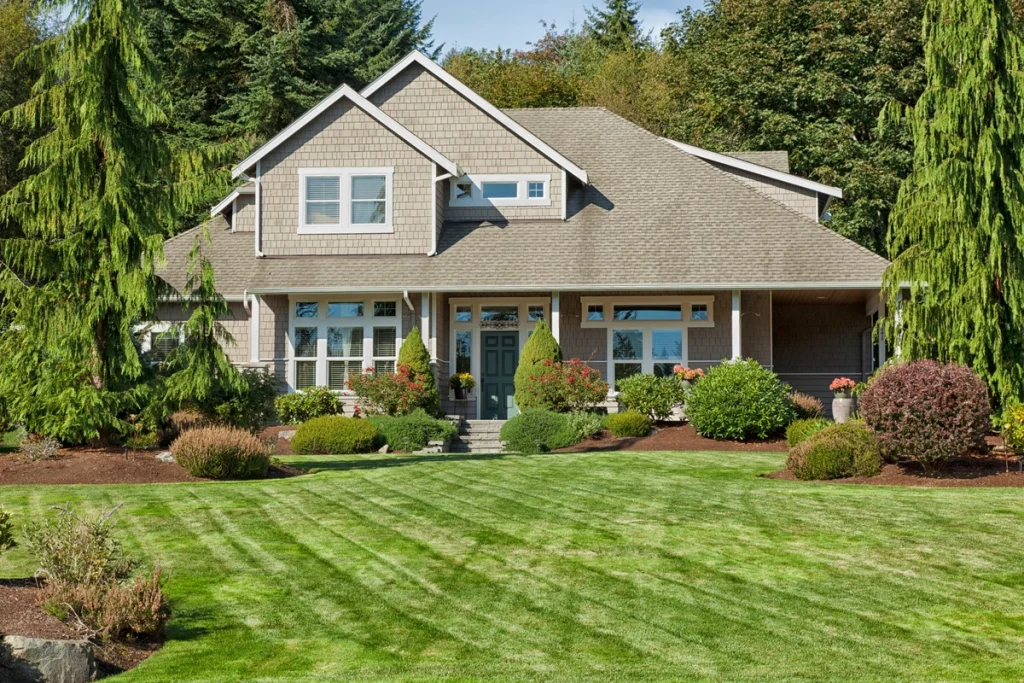 A beautiful suburban house with a meticulously maintained front lawn and a durable new asphalt shingle exterior, providing homeowners lasting protection and the ultimate security of a comprehensive roof warranty.