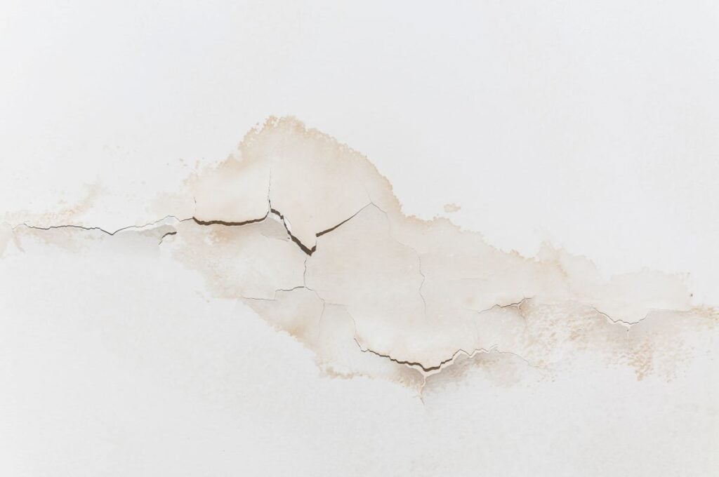 Big wet spots and cracks on the ceiling of the domestic house room after heavy rain and lot of water
