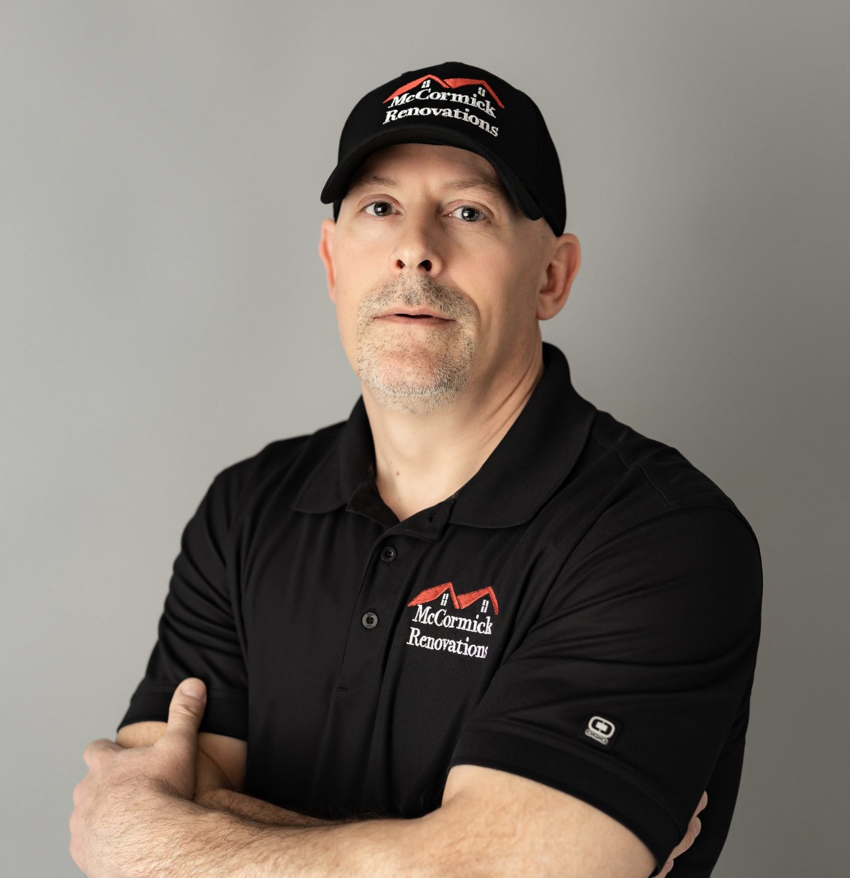 A man wearing a black polo shirt and cap, both with 