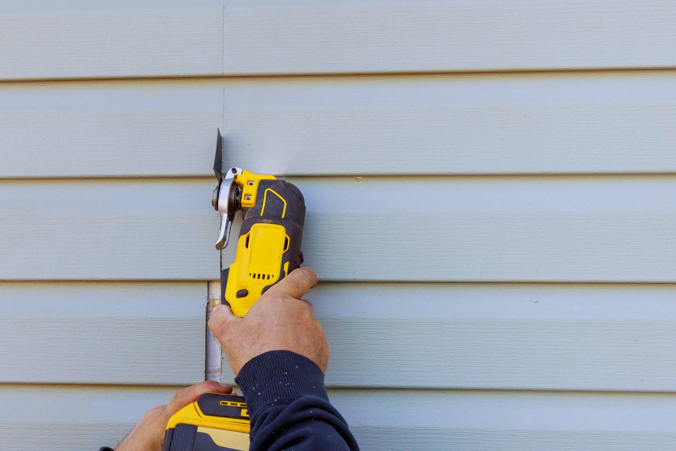 A construction professional installing new light grey horizontal siding on a residential home, providing a high-quality finish that increases curb appeal while helping homeowners manage their overall siding replacement cost