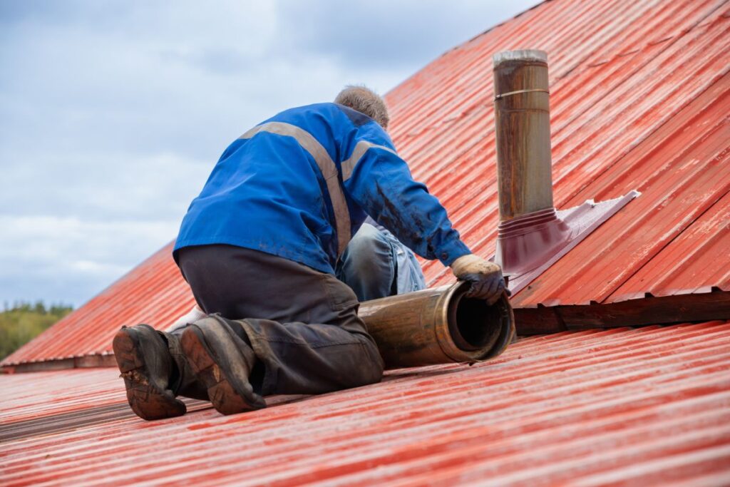 roof ventilation worker installing pipe on metal roof