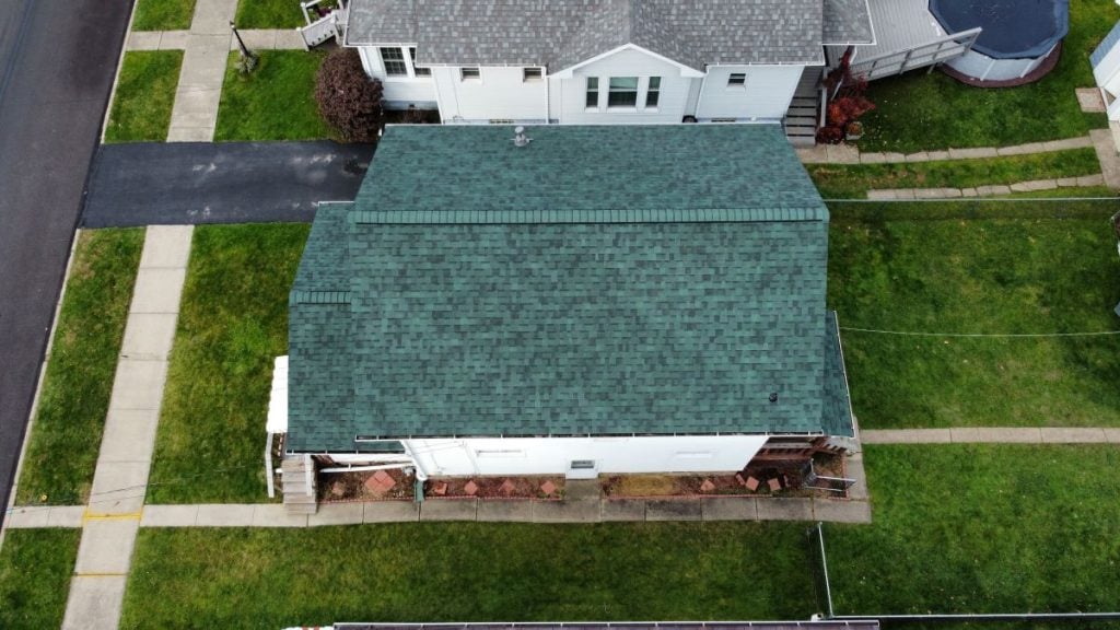 Aerial view of a single-story house with a green shingle roof
