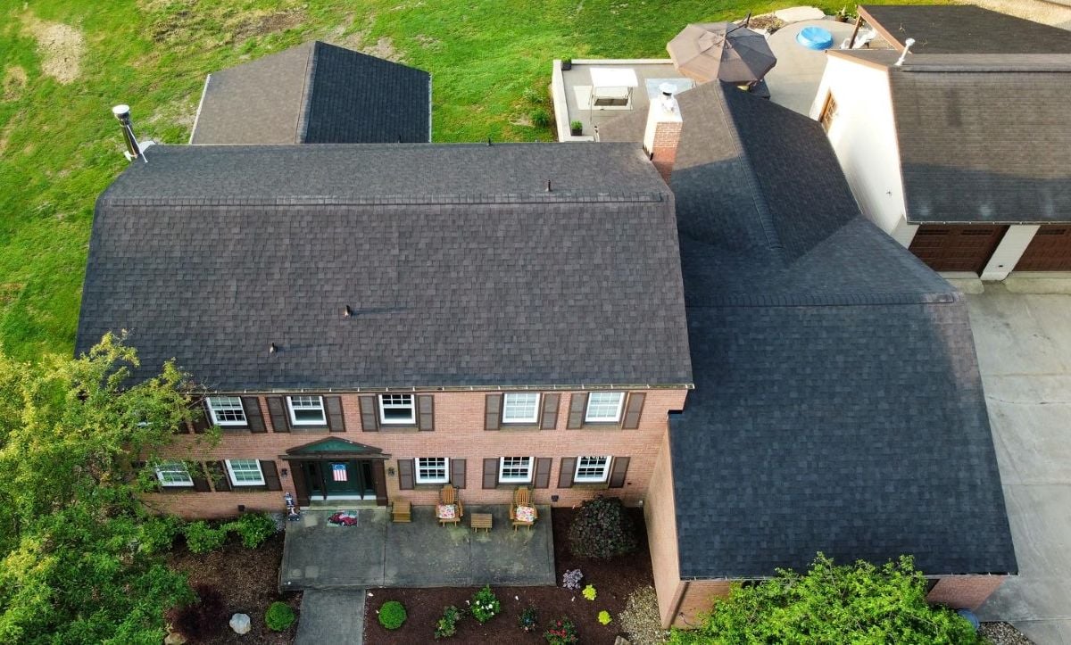 Aerial view of a two-story brick house with dark shingles