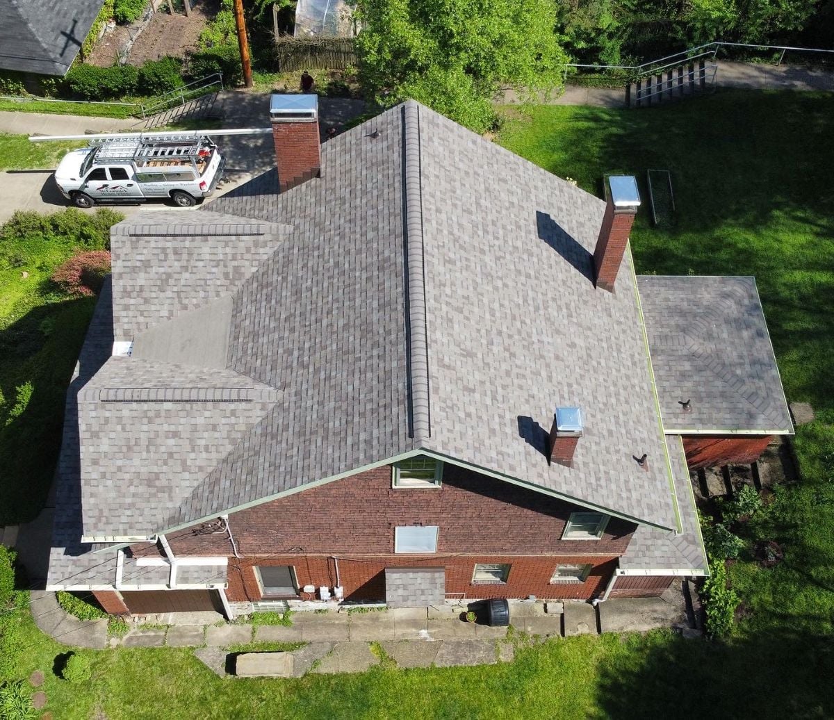 Aerial view of a brick house with a gray shingle roof