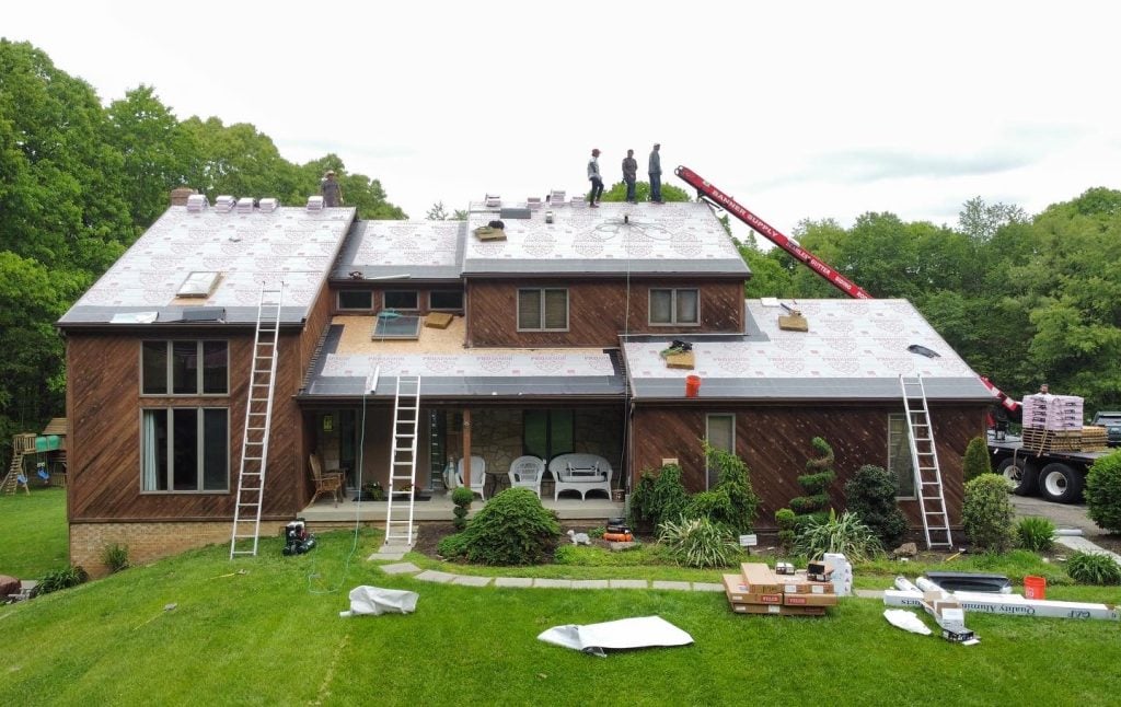 A large house with a wooden exterior is having its roof replaced