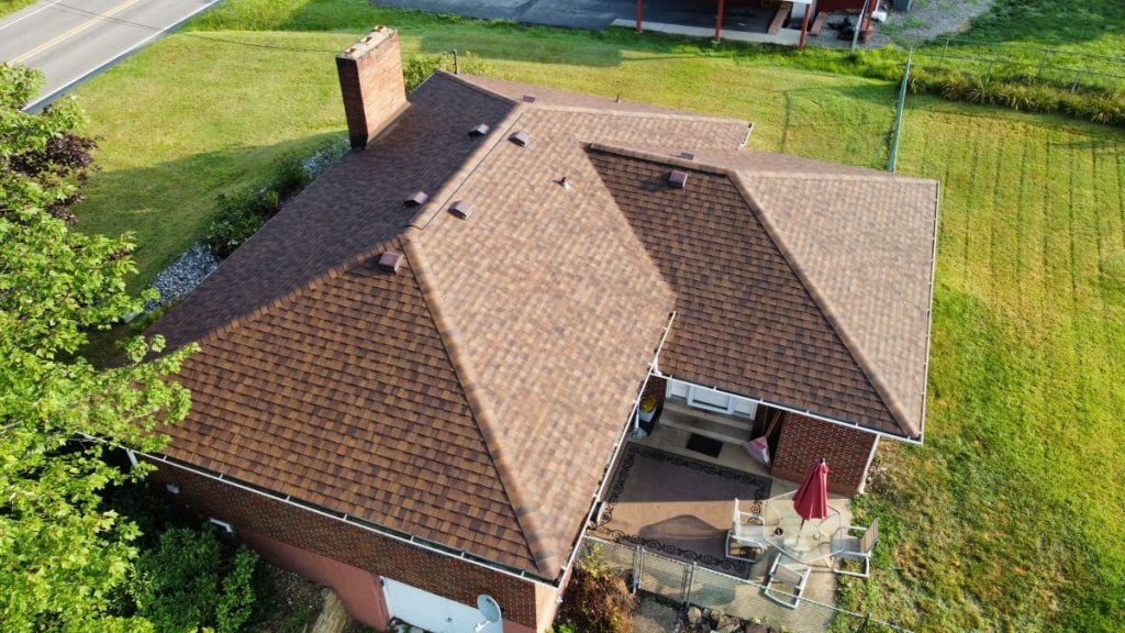 Aerial view of a brick house with a brown shingle roof