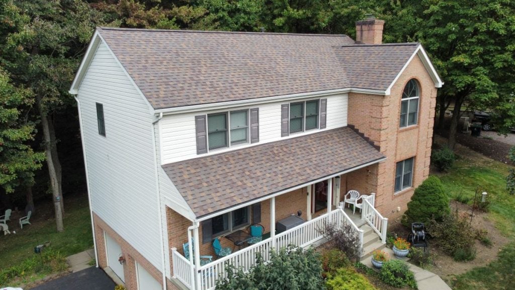 A two-story suburban house with a brick and white siding exterior, shingle roof, front porch 