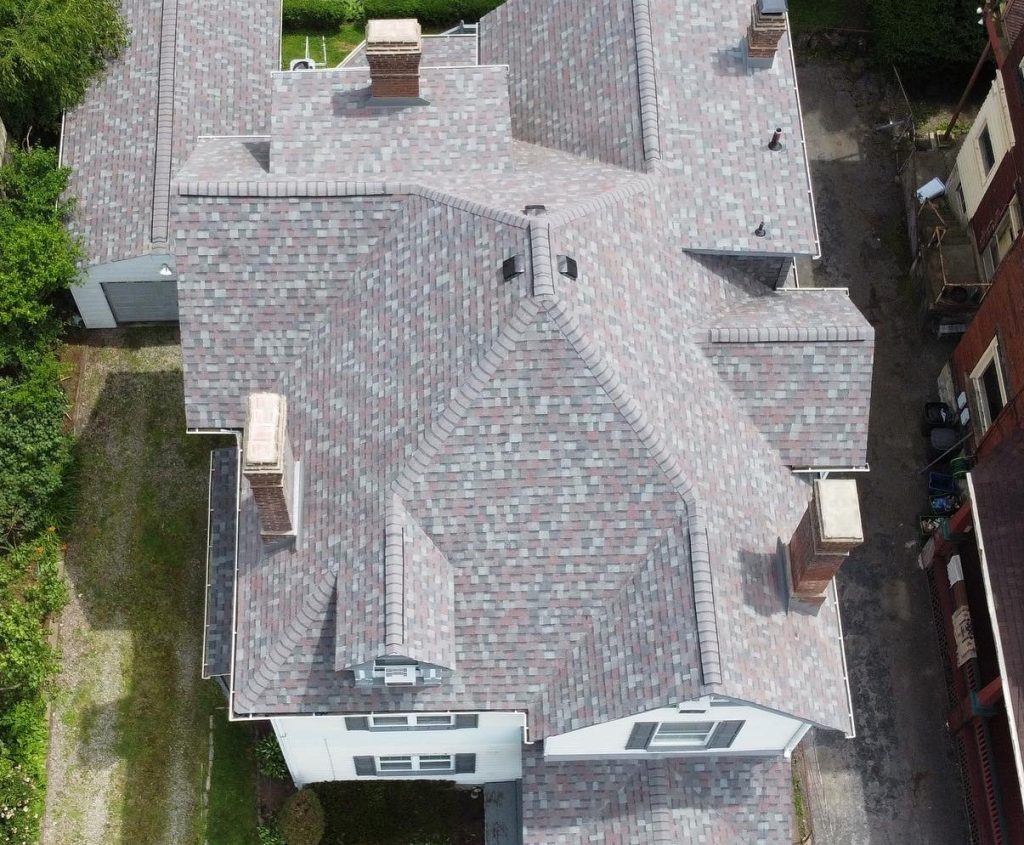 Aerial view of a large house with a complex, multi-gabled gray shingle roof 