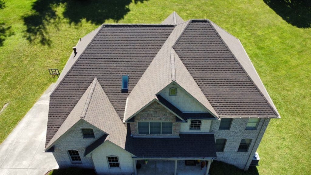 Aerial view of a two-story brick house with a large, clean roof, expertly maintained
