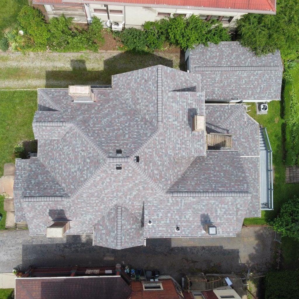 Aerial view of a large, multi-gabled house with grey shingles