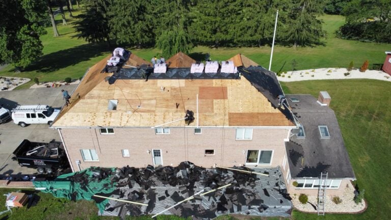 roofing companies in Allison Park workers removing shingles big building