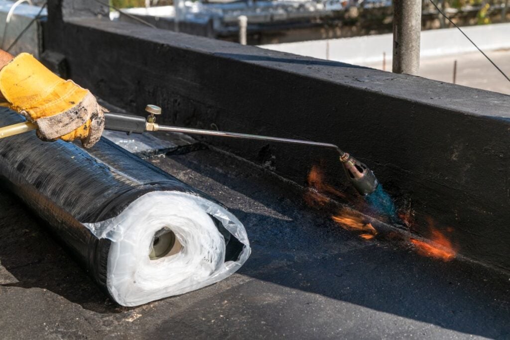 torch down roofing worker applying hot to bitumen
