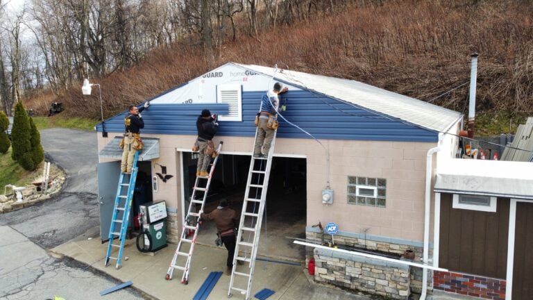 siding companies in Pittsburgh workers replacing blue siding small warehouse