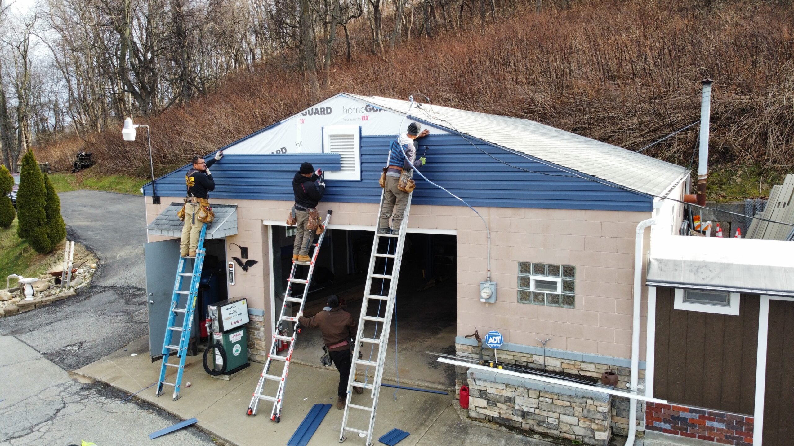 siding companies in Pittsburgh workers replacing blue siding small warehouse