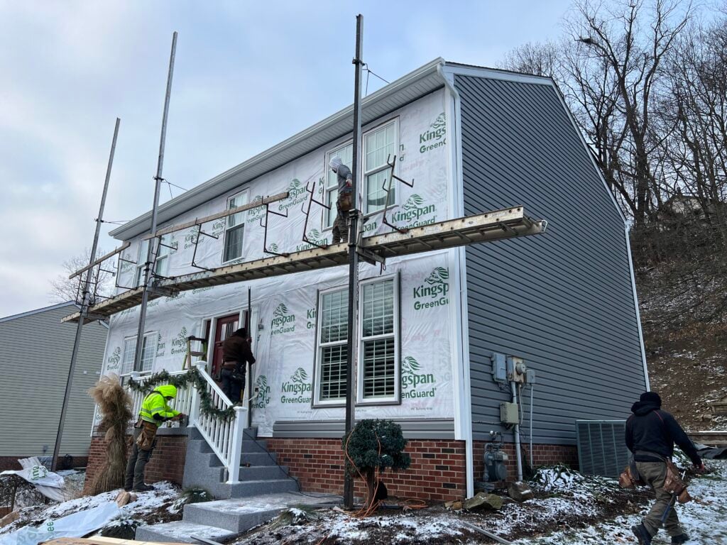 siding companies in Trafford house covered with paper workers replacing blue siding