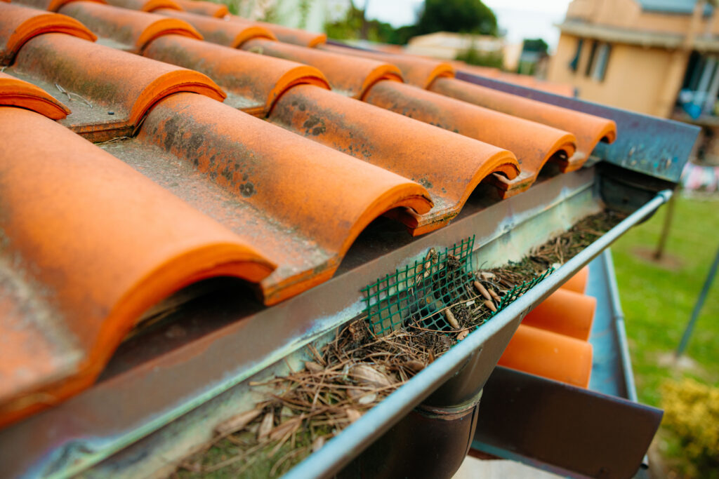 clogged gutters Gutter filled with debris needs cleaning to prevent water damage to house