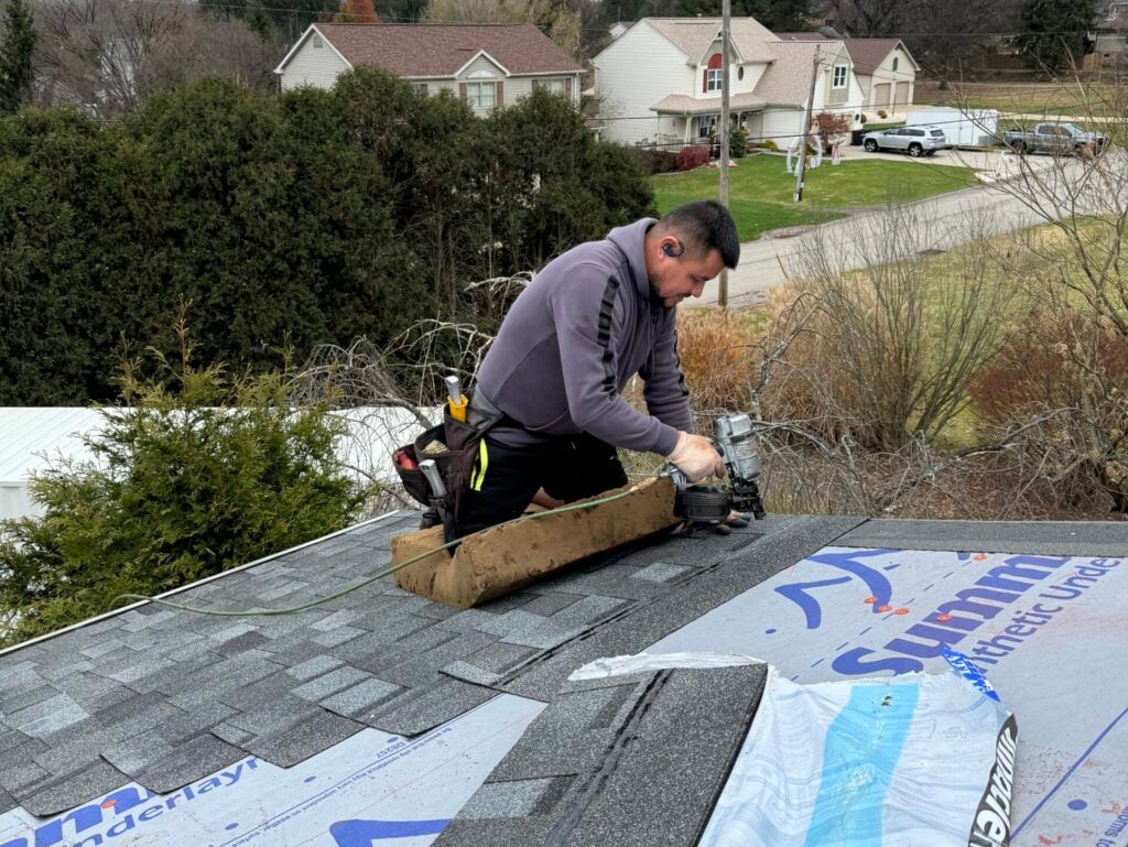 roof replacement cost Irwin worker replacing shingles