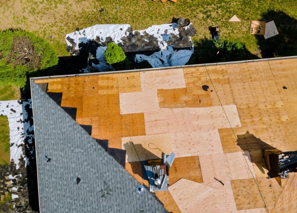 A roofer nailing shingles with air gun, replacing roof cover protection being applied