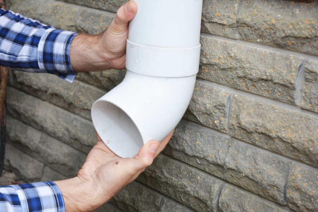 A building contractor is installing new rain gutter system